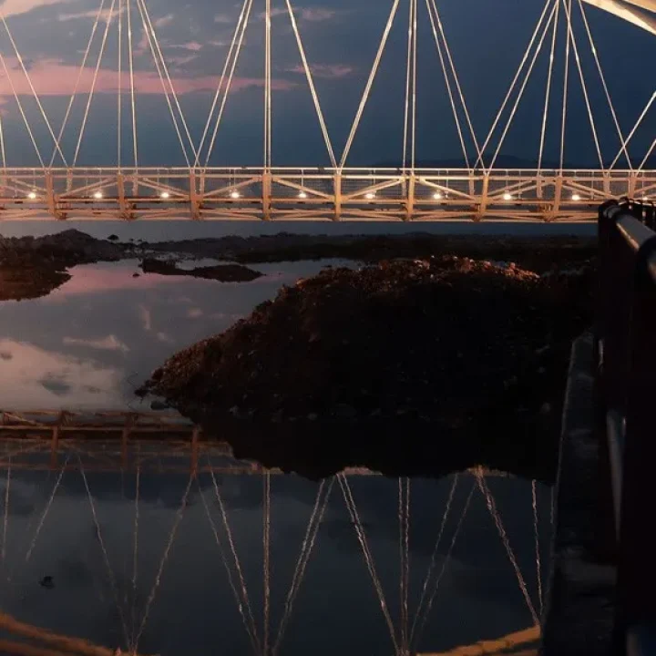 realistic photo featuring a hanging modern bridge over the sea at dusk